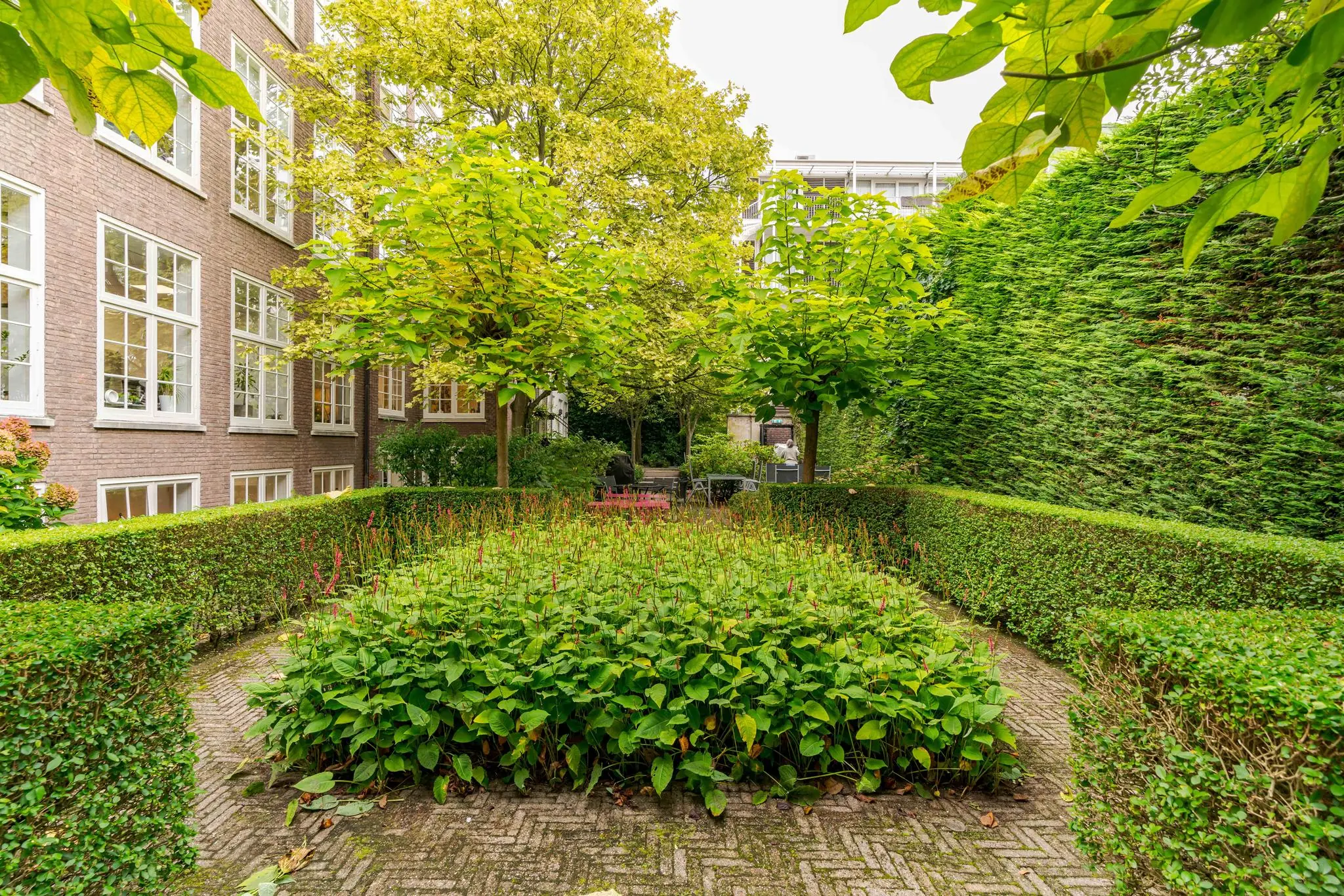 Verzorgde binnentuin met bloemperken, hagen en bomen aan het Lange Voorhout in Den Haag.